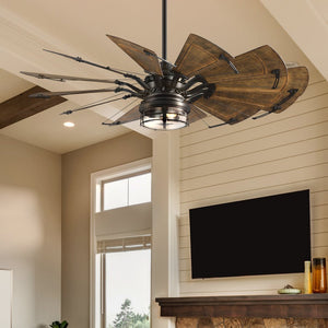 The Urban Ambiance UHP9479 Tuscan Indoor Ceiling Fan from the Saybrook Collection, featuring a windmill-inspired design with rustic wooden blades and industrial metal accents in an architectural bronze finish, graces a living room ceiling above a fireplace and TV. Dimensions: 26-1/4''H x 60"W x 60''D.